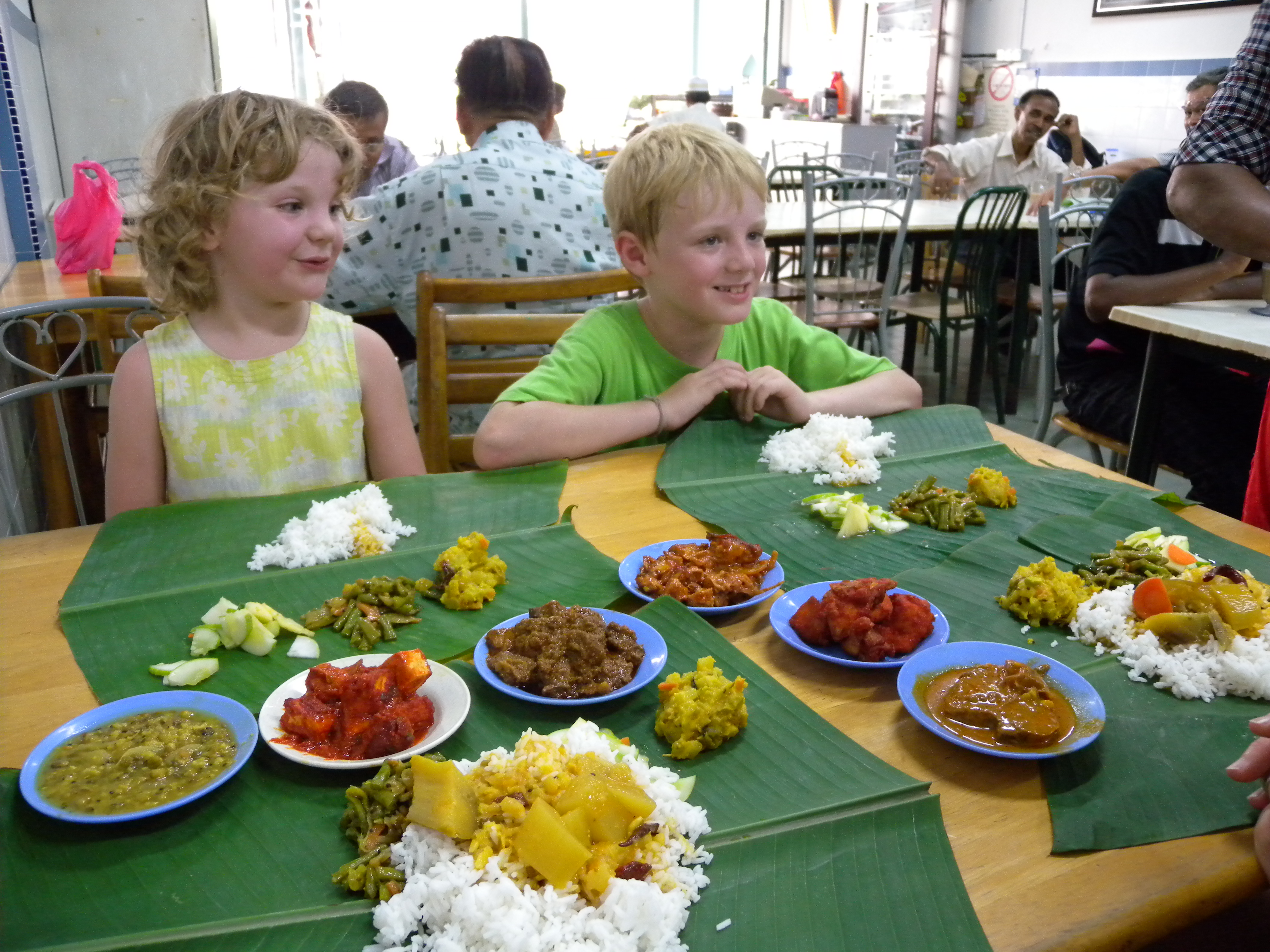 A traditional Tamil feast served on a banana leaf with guests seated on floor mats